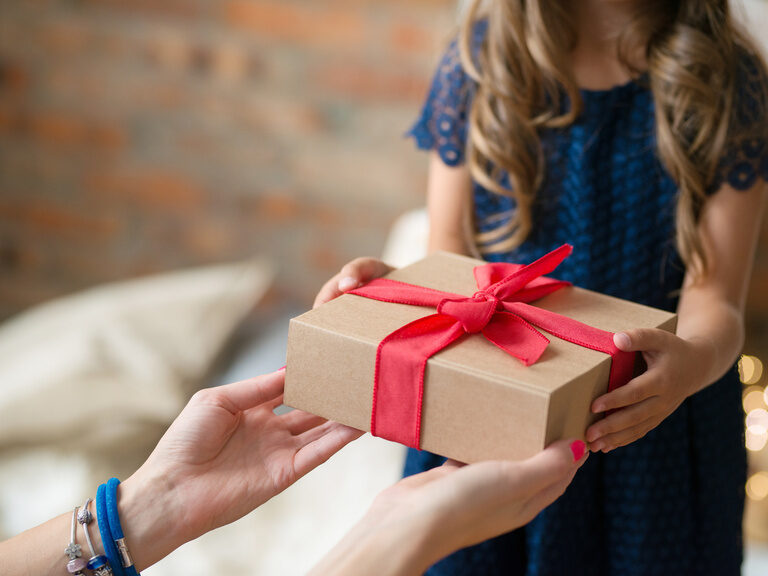 Hände übergeben ein schick verpacktes Geschenk