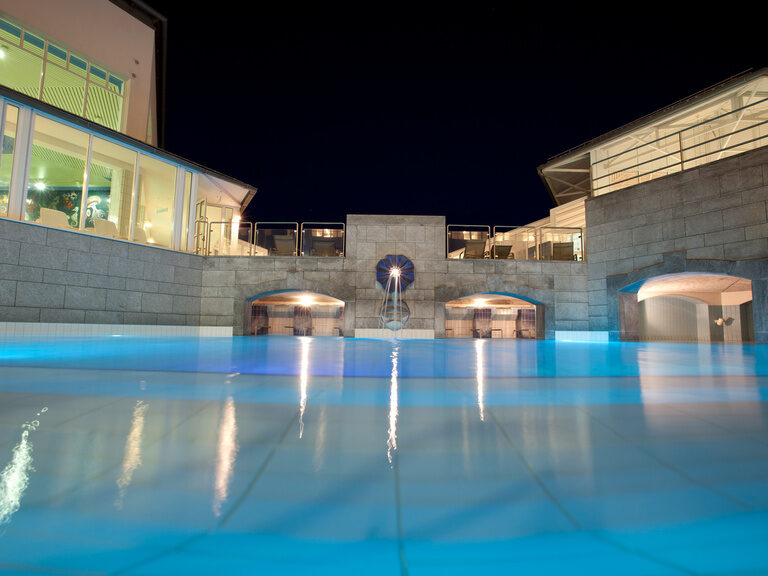 Blick über die Wasseroberfläche eines einladenden Hotelpools in Bad Füssing.